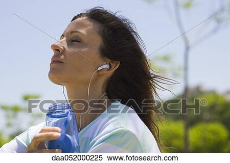 Woman listening to earphones outdoors View Large Photo Image Stock Photography - Woman listening to earphones outdoors. Fotosearch