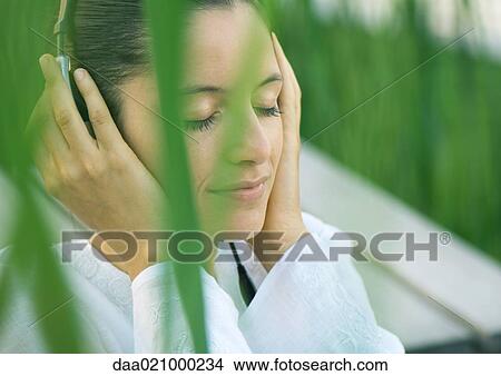 Woman listening to headphones, eyes closed, hands over ears View Large Photo Image Picture - Woman listening to headphones, eyes closed, hands over ears. Fotosearch