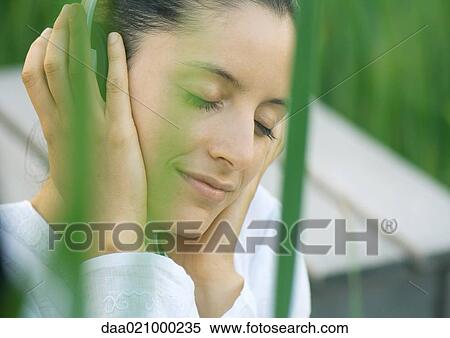 Woman listening to headphones, eyes closed, hands over ears View Large Photo Image Stock Photography - Woman listening to headphones, eyes closed, hands over ears. Fotosearch