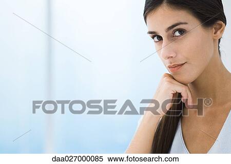 Stock Photography - Woman looking at camera, hand under chin, cropped, portrait. Fotosearch