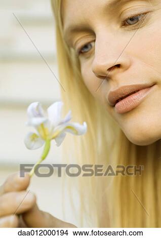 Picture - Woman looking at flower, close-up. Fotosearch