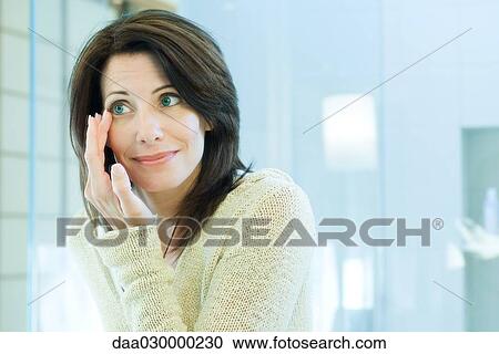 Woman looking at herself in mirror, touching corner of eye View Large Photo Image Stock Image - Woman looking at herself in mirror, touching corner of eye. Fotosearch