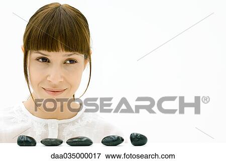 Woman looking away over five stones in a line View Large Photo Image Stock Photo - Woman looking away over five stones in a line. Fotosearch