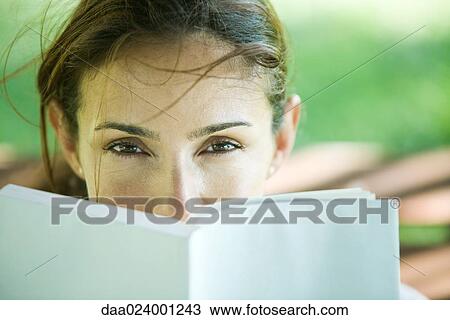 Stock Image - Woman looking over book. Fotosearch