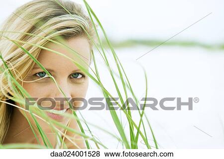 Stock Photo - Woman looking through grass, close-up. Fotosearch