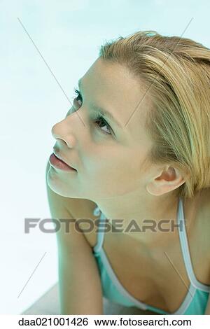 Stock Photograph - Woman lying by pool, looking up, close-up portrait. Fotosearch