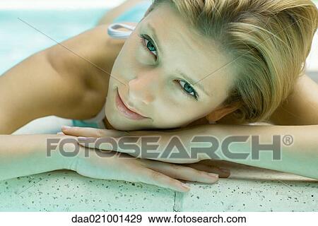 Woman lying by pool, resting head on hands View Large Photo Image Stock Photo - Woman lying by pool, resting head on hands. Fotosearch