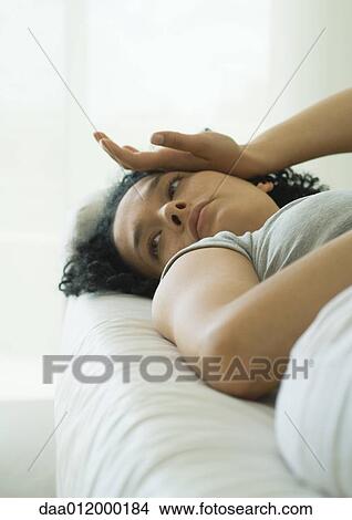 Picture - Woman lying down, looking away, hand on face. Fotosearch