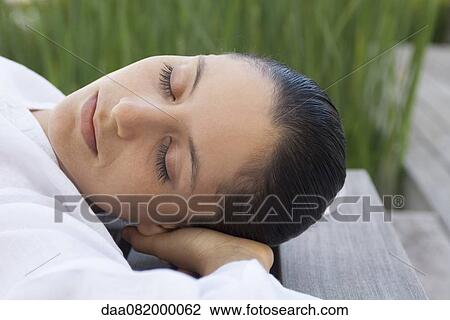 Woman lying down with hands behind head outdoors View Large Photo Image Stock Image - Woman lying down with hands behind head outdoors. Fotosearch