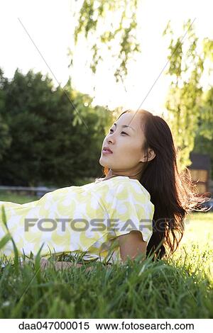 Woman lying in grass, looking away View Large Photo Image Stock Photography - Woman lying in grass, looking away. Fotosearch