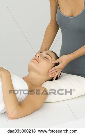 Stock Photo - Woman lying on back, receiving facial massage. Fotosearch
