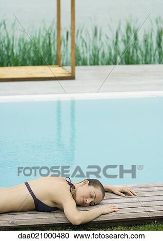 Woman lying on deck near pool, lake in background View Large Photo Image Stock Image - Woman lying on deck near pool, lake in background. Fotosearch