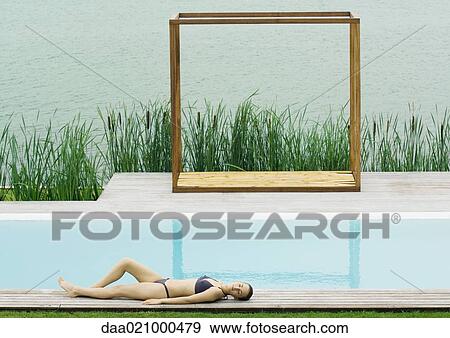 Woman lying on deck near pool, lake in background View Large Photo Image Stock Photo - Woman lying on deck near pool, lake in background. Fotosearch