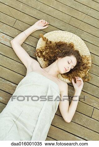 Stock Photography - Woman lying on deck, wrapped in towel, head on mat. Fotosearch