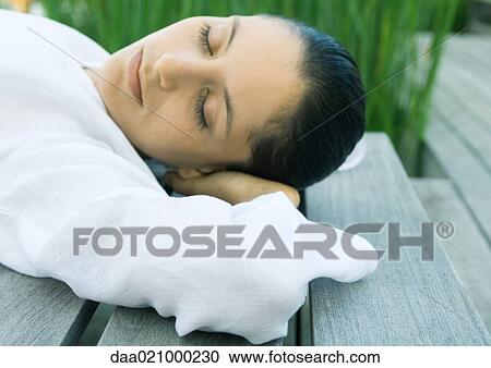 Woman lying on decking, hands behind head View Large Photo Image Stock Image - Woman lying on decking, hands behind head. Fotosearch
