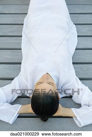 Woman lying on decking, hands behind head, high angle view View Large Photo Image Stock Photo - Woman lying on decking, hands behind head, high angle view. Fotosearch