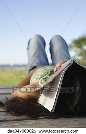Woman lying on dock with magazine covering her face View Large Photo Image Stock Photography - Woman lying on dock with magazine covering her face. Fotosearch
