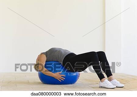 Stock Image - Woman lying on fitness ball. Fotosearch