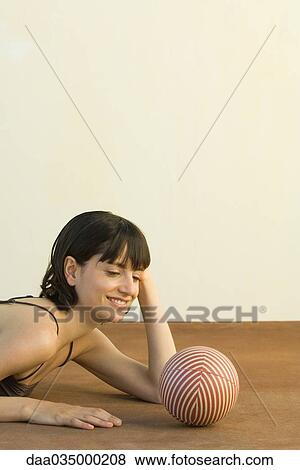 Woman lying on floor, contemplating striped sphere View Large Photo Image Stock Photo - Woman lying on floor, contemplating striped sphere. Fotosearch
