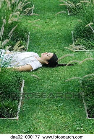 Woman lying on grass, eyes closed View Large Photo Image Stock Photo - Woman lying on grass, eyes closed. Fotosearch