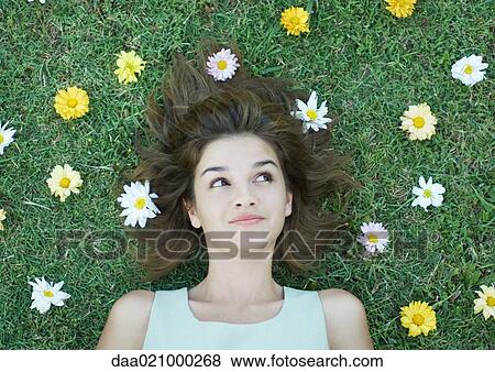Woman lying on grass with flowers scattered around head View Large Photo Image Stock Photo - Woman lying on grass with flowers scattered around head. Fotosearch