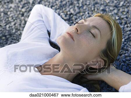 Woman lying on gravel with hands behind head, eyes closed View Large Photo Image Stock Photo - Woman lying on gravel with hands behind head, eyes closed. Fotosearch