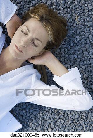 Woman lying on gravel with hands behind head, eyes closed View Large Photo Image Stock Photography - Woman lying on gravel with hands behind head, eyes closed. Fotosearch