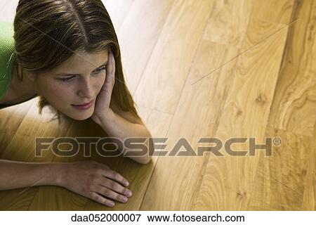 Woman lying on hardwood floor, looking away View Large Photo Image Stock Photo - Woman lying on hardwood floor, looking away. Fotosearch