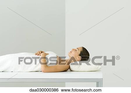 Woman lying on massage table, eyes closed View Large Photo Image Stock Photograph - Woman lying on massage table, eyes closed. Fotosearch