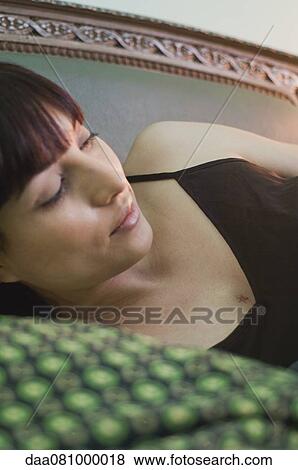 Stock Photo - Woman lying on side, looking away in thought. Fotosearch