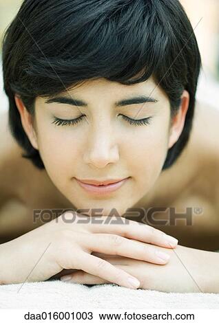 Stock Image - Woman lying on stomach, head on hands. Fotosearch