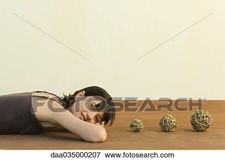 Woman lying on stomach, head resting on arms, three balls of braided twine set in row at head View Large Photo Image Stock Photo - Woman lying on stomach, head resting on arms, three balls of braided twine set in row at head. Fotosearch