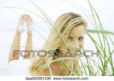 Woman lying on stomach, looking through grass, close-up View Large Photo Image Stock Image - Woman lying on stomach, looking through grass, close-up. Fotosearch