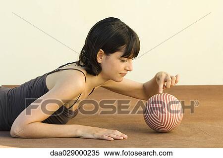 Woman lying on stomach, touching ball with finger, side view View Large Photo Image Stock Photography - Woman lying on stomach, touching ball with finger, side view. Fotosearch