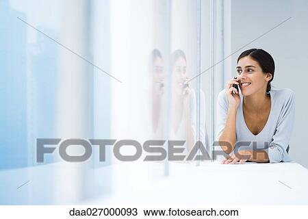 Woman lying on stomach, using cell phone, looking out window View Large Photo Image Stock Image - Woman lying on stomach, using cell phone, looking out window. Fotosearch