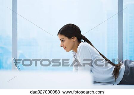 Woman lying on stomach using laptop, side view View Large Photo Image Stock Photo - Woman lying on stomach using laptop, side view. Fotosearch