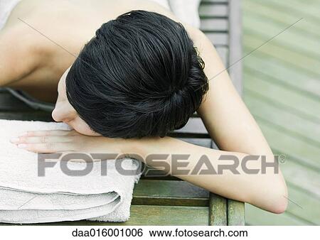 Stock Photograph - Woman lying on stomach, wrapped in towel, head on hand. Fotosearch