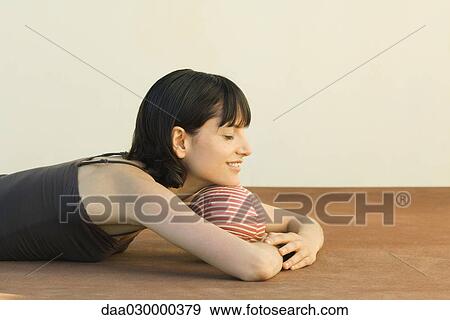 Stock Photo - Woman lying on the ground, resting head on ball, eyes closed. Fotosearch