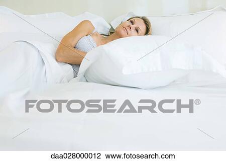 Woman lying with head on pillow, looking up, smiling View Large Photo Image Stock Image - Woman lying with head on pillow, looking up, smiling. Fotosearch