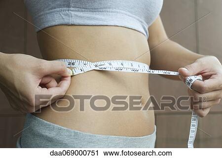 Woman measuring her waist with measuring tape, cropped View Large Photo Image Stock Image - Woman measuring her waist with measuring tape, cropped. Fotosearch