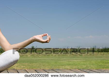 Stock Photograph - Woman meditating outdoors, cropped view. Fotosearch