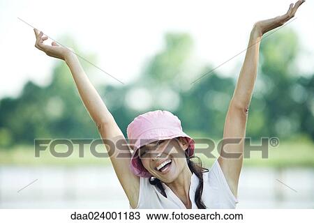 Woman outdoors, arms in the air, smiling at camera, portrait View Large Photo Image Stock Image - Woman outdoors, arms in the air, smiling at camera, portrait. Fotosearch
