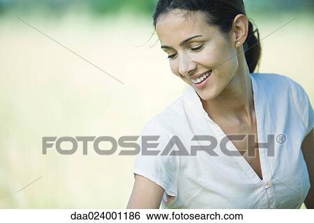 Woman outdoors, smiling and looking down, head and shoulders View Large Photo Image Stock Photograph - Woman outdoors, smiling and looking down, head and shoulders. Fotosearch
