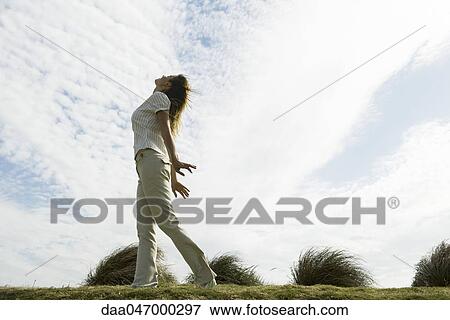 Stock Photo - Woman outdoors standing with arms out, head back. Fotosearch