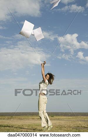 Woman outdoors tossing document into air View Large Photo Image Picture - Woman outdoors tossing document into air. Fotosearch