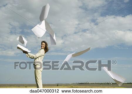 Woman outdoors tossing document into air watching pages caught by wind fly away View Large Photo Image Stock Image - Woman outdoors tossing document into air watching pages caught by wind fly away. Fotosearch