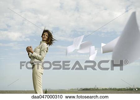 Woman outdoors watching documents caught in wind fly away View Large Photo Image Stock Image - Woman outdoors watching documents caught in wind fly away. Fotosearch