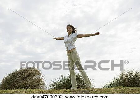 Stock Image - Woman outdoors with arms outstretched. Fotosearch