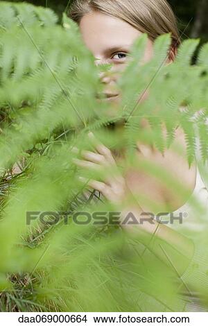 Picture - Woman peeking through fern frond, portrait. Fotosearch