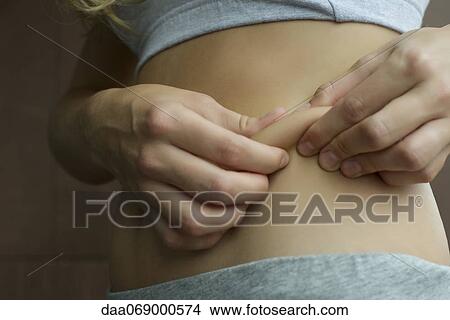 Woman pinching fat on her waist, cropped View Large Photo Image Picture - Woman pinching fat on her waist, cropped. Fotosearch
